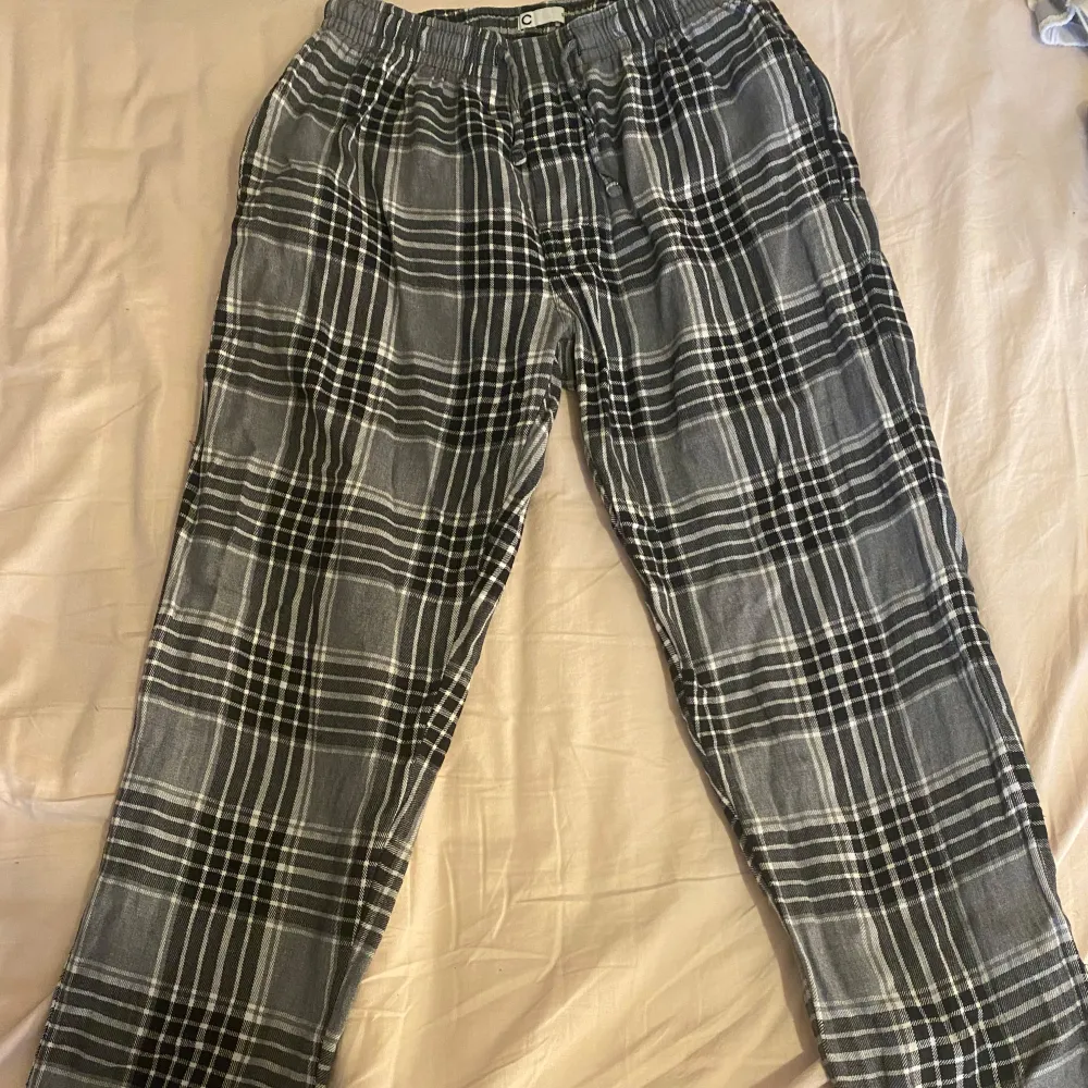 Säljer ett par bekväma svartvitrutiga byxor med elastisk midja och snörning från man avdelningen . Byxorna har en klassisk rutig design och är gjorda i ett mjukt material.. Farkut & Housut.