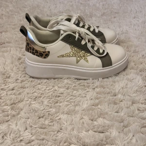 Golden goose likanade sneakers - Snygga vita sneakers med en glittrig stjärna på sidan och leopardmönstrade detaljer vid hälen. Skorna har vita snören och en bekväm rund tå. Perfekta för att ge din outfit en extra touch. Använda 2 gånger. Storlek 39💕