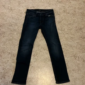 Mörkblå jeans från Jack & Jones - Säljer ett par mörkblå jeans från Jack & Jones, modell Slim/Glenn. De har en slim passform och är tillverkade av bomull. Perfekta för en stilren look.
