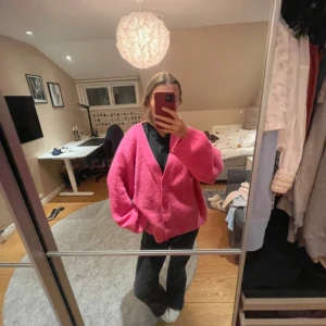 Rosa kofta med knappar - Säljer en mysig rosa kofta med knappar framtill. Koftan har en oversized passform och långa ärmar, perfekt för en avslappnad stil. Den är enkel att matcha med olika outfits och ger en färgglad touch till garderoben.