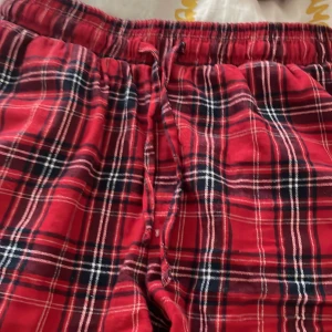 Röda rutiga pyjamasshorts med snörning - Säljer ett par bekväma röda pyjamasshorts med rutig design och snörning i midjan. Perfekta för en avslappnad stil.
