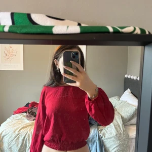 Röd långärmad tröja - Säljer en snygg röd långärmad tröja med elastisk nederkant. Perfekt för en avslappnad stil och enkel att matcha med jeans eller kjol. Hör av dig vid intresse!