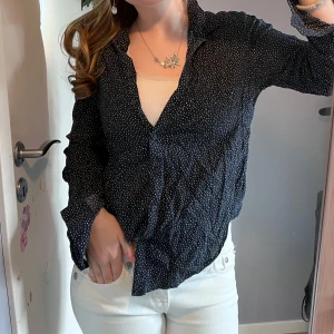 Svart prickig blus - Snygg svart blus med vita prickar och knappar framtill. Perfekt för en stilren look. Blusen har långa ärmar och en klassisk krage. Den är ifrån Lindex!! Vid mer frågor är det bara att kontakta!!💕🎀🙏