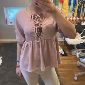 Rosa blus med knytning - Säljer en söt rosa blus med knytning framtill. Blusen har trekvartsärmar och en luftig passform som ger en avslappnad look. Perfekt för vår och sommar!