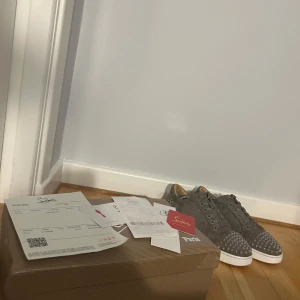 Gråa sneakers med nitar från Christian Louboutin - Gråa Christian Louboutin med nitar och den ikoniska röda sulan. OBS !! ALLT OG INGÅR, pris kan diskuteras vid snabb affär