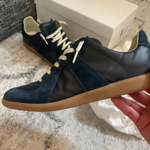 Blå sneakers från Maison Margiela - Snygga blå sneakers från Maison Margiela med en stilren design. Helt nya och! Säljer pågrund av att dom inte passa mig. Allt som ni ser i bilderna följer med! Riktigt feta. Hör av dig vid funderingar!!