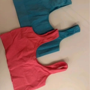 Ribbad topp i blått och rosa - Säljer två ribbade  toppar i blått och rosa. Perfekta för en trendig look med en unik design. Passar bra till både jeans och kjol men även träning - inga pads i