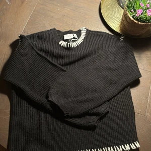 Svart stickad tröja från VILA - Säljer en svart stickad tröja från VILA med vita detaljer runt halsen och nederkanten. Tröjan har långa ärmar och en ribbad struktur som ger en stilren look. Perfekt för våren! Köpt ganska dyr, men priset kan defenitivt diskuteras 💘