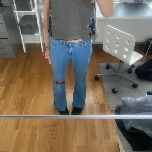 Blå lowwaist bootcut jeans - Säljer dessa jeansen då de är för korta, bilderna är gamla men har inte använt de sen dessa bilder togs. De är lite pösiga på mig och har en slits på båda sidorna. Midjan är justerbar.