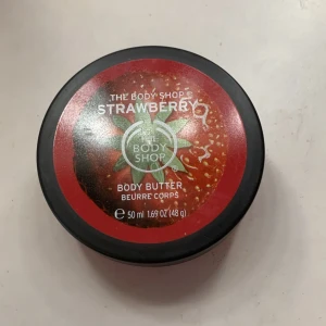 Body Butter Strawberry från The Body Shop - Härlig body butter med jordgubbsdoft från The Body Shop. Kommer i en praktisk burk på 50 ml. Perfekt för att återfukta och mjukgöra huden med en fruktig doft.