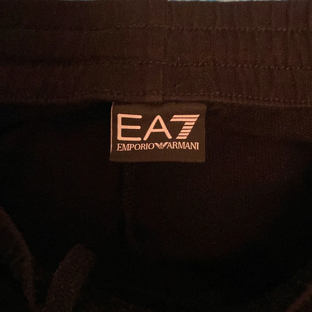 Snygga svarta mjukisbyxor från Emporio Armani med EA7-logga i guld. Byxorna har en bekväm passform med snörning i midjan och är perfekta för en avslappnad stil. Säljer pga för små sparsamt använda.. Farkut & Housut.