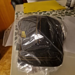 Mcdonalds keps  - Helt ny mcdonalds keps.  Perfekt för dig som älskar streetwear, samlar på unika plagg eller bara vill sticka ut med en ikonisk look. Svart med klassisk McDonald’s-logga – stilren och retro på samma gång.