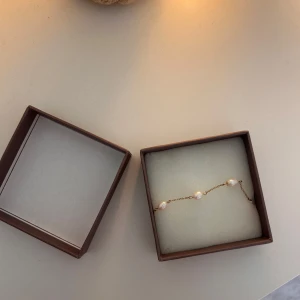 Guldarmband med pärlor från Edblad -  guldarmband från Edblad med vita pärlor. Säljer då jag. fick likadant i present. Kommer i originalförpackning. Använt 3/4 gånger 