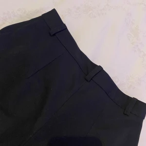 Svarta kostymbyxor från Etam - Snygga svarta kostymbyxor från lager 157 i en klassisk design. Byxorna har utsvängdaben, vilket ger en stilren look. Perfekta för en elegant stil.