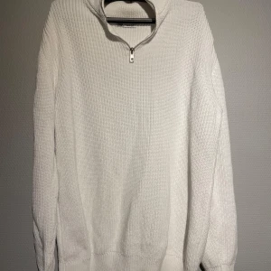 Vit stickad tröja från Zara - Säljer en stilren vit stickad tröja från Zara med dragkedja vid halsen. Perfekt för kyligare dagar med sin mjuka och bekväma passform. Tröjan har långa ärmar och ribbade kanter för extra komfort. Passar både till vardags och mer uppklädda tillfällen.