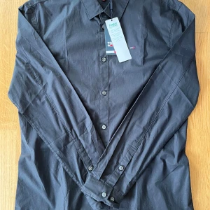 Tommy Hilfiger skjorta - Säljer nu denna snygga Tommy Hilfiger skjortan i storlek L. Den är helt ny, lappen sitter till och med kvar. Den är svart med en broderad logga på bröstet. Tveka inte att ställa några frågor om ni undrar något.