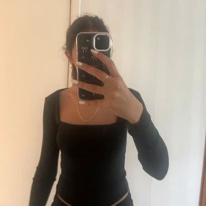 Svart långärmad topp med fyrkantig ringning - Säljer en svart långärmad topp med snygg fyrkantig ringning. Toppen är tight och har en stilren, minimalistisk look som passar perfekt till jeans eller kjol. Mjuk och stretchig i materialet för en bekväm passform.