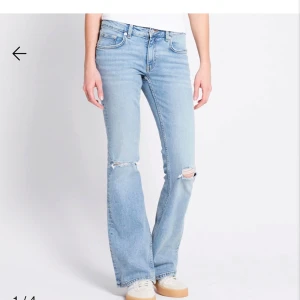 Ljusblå bootcut jeans med slitningar - Snygga ljusblå jeans med bootcut passform och slitna detaljer vid knäna. Klassisk femficksmodell i mjukt denimtyg, perfekt för en avslappnad och trendig look. Midja i normalhöjd och raka ben som blir vidare nertill.