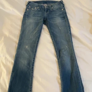 Ljusblå bootcut low waist jeans - True religion jeans med snygga slitningar. Är i storlek 32 tror jag.