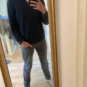 Mörkblå stickad tröja Polo Ralph Lauren - Säljer en mörkblå stickad tröja från Polo Ralph Lauren med halv dragkedja och röd broderad logga på bröstet. Tröjan har knappt blivit använd, har inga slitningar/fläckar/hål. PRISET ÄR INTE HUGGET I STEN