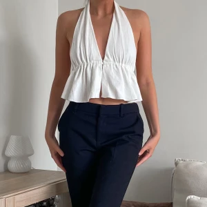 Vit halterneck top  - Säljer en vit croppad halterneck topp med djup v-ringning och volang nedtill.