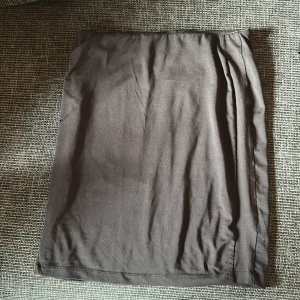 Svart långkjol från Gina Tricot - En svart långkjol från Gina Tricot i mjukt material med enkel och stilren design. Kjolen är rak i modellen och har resår i midjan för en bekväm passform. Perfekt att styla med sneakers eller boots.