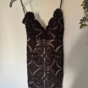 Spetsklänning  - Kort klänning med spets och smala axelband. Djup v-ringning och figurnära passform. Aldrig använd 