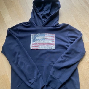Marinblå hoodie Ralph Lauren M - Snygg marinblå hoodie från Ralph Lauren Denim & Supply med amerikansk flagga tryckt på bröstet. 