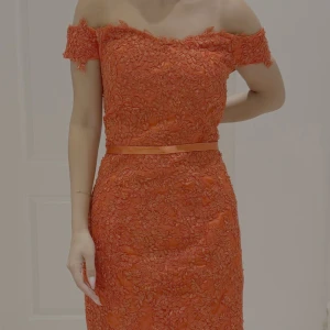 Röd långklänning med spets och offshoulder - Snygg röd långklänning med offshoulder och figurnära passform. Klänningen har vackra spetsdetaljer, markerad midja med satinband och knappar längs ryggen. Utsvängd nederdel med släp och blommiga broderier ger en lyxig känsla.