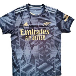  Arsenal bortatröja 2022/23 - Officiell Adidas-tröja med "Emirates Fly Better"-tryck och ikoniskt mönster i svart och grått. Perfekt för fans eller som stilren streetwear. Endast använd ett fåtal gånger – i toppskick! 💯 * S: 165-175 CM, 60-70KG Skicka meddelande vid intresse! ⚽👕
