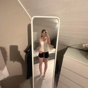 Svarta träningsshorts med gula detaljer - Svarta träningsshorts med vita snören i midjan och gula ränder på sidorna. De har en sportig look och är perfekta för gymmet eller löprundan. Modellen är kort och har en loose passform med elastisk midja för extra komfort.