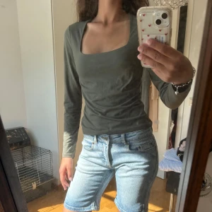 Mörkgrön långärmad topp från H&M - Säljer en mörkgrön långärmad topp från H&M i storlek S. Toppen har en snygg fyrkantig urringning. Perfekt att styla med jeans eller kjol för en clean look.