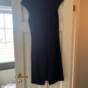 Marinblå kortklänning Patrizia Pepe - Stilren marinblå kortklänning från Patrizia Pepe med v-ringning och ärmlös design. Klänningen har en figurnära passform och är tillverkad i ett mjukt material som ger en elegant siluett. Perfekt för dig som gillar klassisk och tidlös stil. Itskiensk 40 som motsvarar 36 i Sverige 