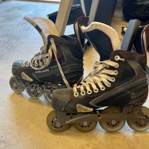 Svarta Bauer inlines med snörning - Säljer ett par svarta Bauer inlines med vita snören och röda detaljer. Skorna har robust design, högt skaft och flera ventilationszoner. Perfekta för dig som gillar fart och streetstyle. Hjul i slitstarkt material och klassisk hockeylook. Använda fåtal gånger och är i mycket bra skick 