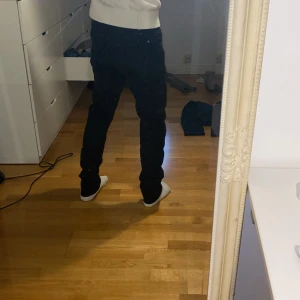 Svarta jeans Tiger of Sweden IGGY 33/32 - Svarta jeans från Tiger of Sweden i modellen IGGY. Klassisk femficksdesign, rak passform och normal midja. Snygga och stilrena jeans i svart denim som passar perfekt till en clean och modern look.
