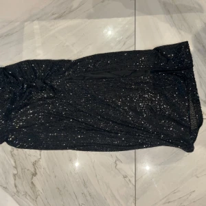 Svart glittrig kjol Stockh LM - Supersnygg svart kjol från Stockh LM i storlek XS. Kjolen är täckt av glittriga paljetter och har en slits på sidan för extra edge. Materialet känns mjukt och följsamt. Använd en gång! Säljs ej längre. 