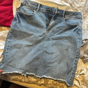 Blå jeanskjol från Pieces, S - Snygg blå jeanskjol från Pieces i klassisk modell med fem fickor, bälteshällor och rå, fransig kant nedtill. Kjolen har dragkedja och knapp framtill och är perfekt för sommaren☺️☺️