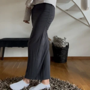 Grå långkjol med rynkade sidor - Säljer en grå långkjol med tight passform och snygga rynkade detaljer från Ginatricot. Kjolen är enkel och stilren, perfekt att matcha med en stickad tröja eller crop top. Säljer då den är lite för liten för mig och är därför i nyskick💕