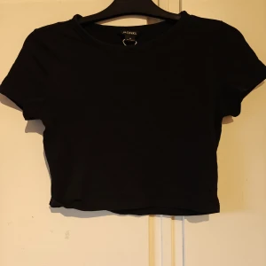 Svart croppad topp från Monki - En svart croppad topp från Monki med rund halsringning och korta ärmar. Enkel och stilren design i mjuk bomull, perfekt att matcha med höga jeans eller kjol. Snygg basic som funkar året runt.