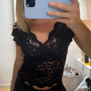 !!INTRESSEKOLL!! Svart spetsblus från Zara - Går att köpa för 399kr direkt! Supersnygg svart blus från Zara i genombruten spets med v-ringning och korta ärmar. Blusen har vågiga kanter och en croppad passform som ger en trendig look. Perfekt att styla med höga jeans eller kjol för en cool outfit.