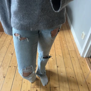 Slitna bootcut jeans - Säljer ett par ljusblå jeans med flera slitningar och hål på låren och knäna. Jeansen är bootcut säljer då jag tyvärr inte använder de längre.