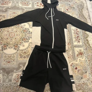Hugo Boss Tracksuit / dress - Jätte fin Svart och vit Hugo boss tränings dress Zip up hoodien/koftan är i storlek S medans kortbyxorna är i storlek M, men tracksuiten sitter bra för någon med storlek S Skicket på den är mycket bra, endast nopprig, ena ändan på snöret har ramlat av och loggan på baksidan av koftan har tappt lite, inget man märker av så länge man inte kollar jätte noggrant  Skicka meddelande vid några funderingar  Kolla gärna även in mina andra annonser