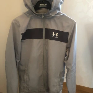 Grå vindjacka från Under Armour  - Skön Underarmour jacka. Inga hål eller slitage! Bara lite smutsig men det går bort genom tvätta den, Storlek S 