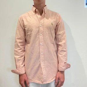 Ljusrosa Ralph Lauren Skjorta - Ljusrosa Ralph lauren skjorta || Storlek M (Slim Fit) || Skjortan är i bra skick, däremot en fläck som syns på bild 3|| Mitt pris 449kr || Modellen på bilden är 170cm och väger 62kg || Tveka inte på att höra av dig vid frågor eller funderingar 