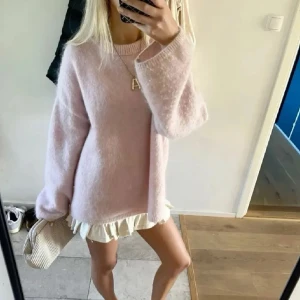 Ljusrosa oversized stickad tröja - Vid köp välj PostNord! Supermysig ljusrosa stickad tröja med oversized passform och långa ärmar. Tröjan har en enkel rund halsringning och är gjord i ett fluffigt, mjukt material som känns lyxigt. Perfekt att styla med kjol eller jeans för en chill look. Den är lite nopprig men inte mycket