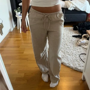 Beiga lågmidjade linnebyxor från Gina Tricot - Säljer ett par beiga linnebyxor från Gina Tricot i storlek S. Byxorna har snörning i midjan, raka ben och en avslappnad passform. Säljer byxorna då jag inte fått användning för de.