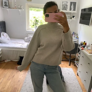 Beige polotröja i ullmix - Säljer en beige polotröja med hög krage och ribbade muddar. Tröjan har en loose passform och är stickad i mjuk ullmix, perfekt för kyliga dagar. Enkel och stilren design som är lätt att matcha med jeans eller kjol.