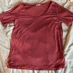 Mörkrosa t-shirt från Filippa K - Enkel och snygg mörkrosa t-shirt från Filippa K med rund halsringning och korta ärmar. T-shirten är i mjuk bomull och har en klassisk passform som funkar till allt. Perfekt basplagg i garderoben!