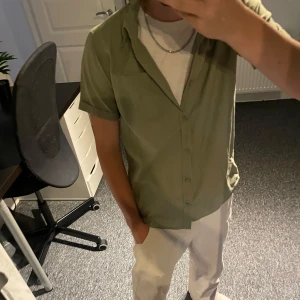 Ljusgrön kortärmad skjorta  - Snygg ljusgrön skjorta med korta ärmar och klassisk krage. Skjortan har knäppning framtill och är tillverkad i mjuk bomull, perfekt för varma dagar. Enkel och stilren design som är lätt att matcha med andra plagg. Modellen är 163 för att gemföra 