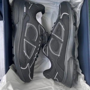 Svarta Dior sneakers med vita detaljer - Snygga svarta Dior sneakers med vita kontrastdetaljer och tydlig CD-logga på sidan. Skorna har en chunky sula, meshpaneler och partier i syntet och skinn. Perfekta för dig som vill ha en exklusiv och modern look med streetkänsla.